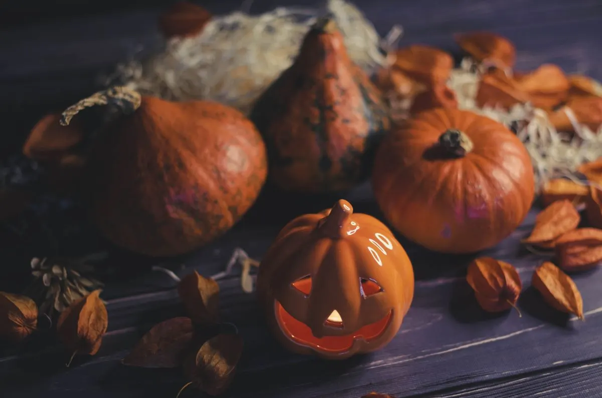 Carved pumpkins and autumn leaves on a dark table